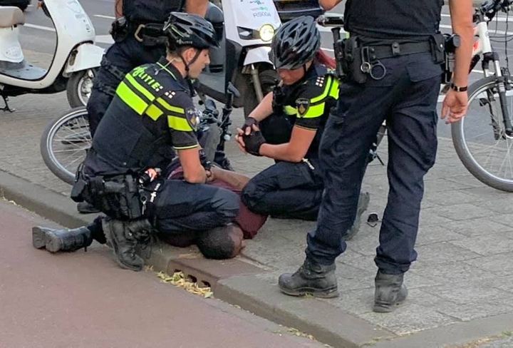 Een man met een donkere huidskleur wordt met fors geweld gearresteerd, volgens een getuige vanwege belediging van een ambtenaar in functie