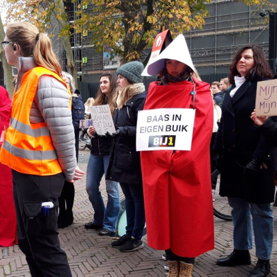 Lid BIJ1 gekleed in kostuum "Handmaid's Tale" met bord "Baas in eigen Buik BIJ1"